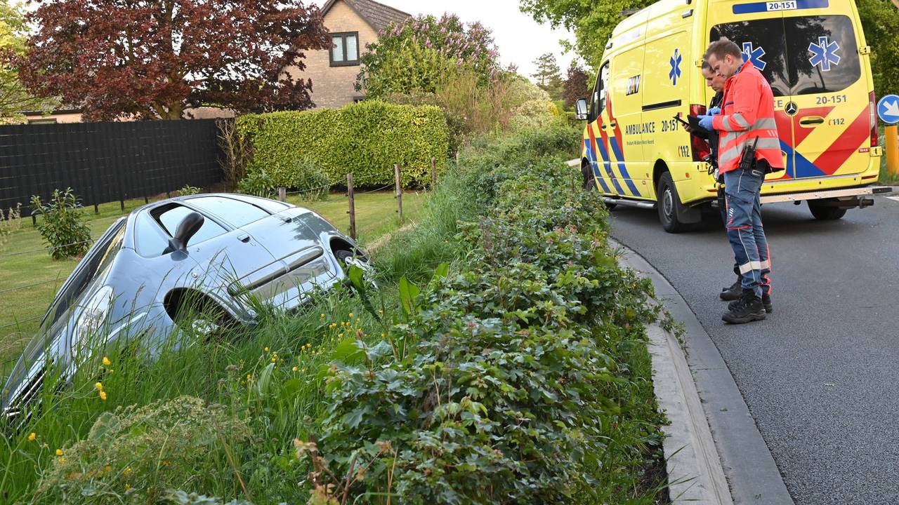 Oudere vrouw rijdt met haar auto in een sloot, omstanders schieten te hulp (foto: Perry Roovers/Persbureau Heitink).