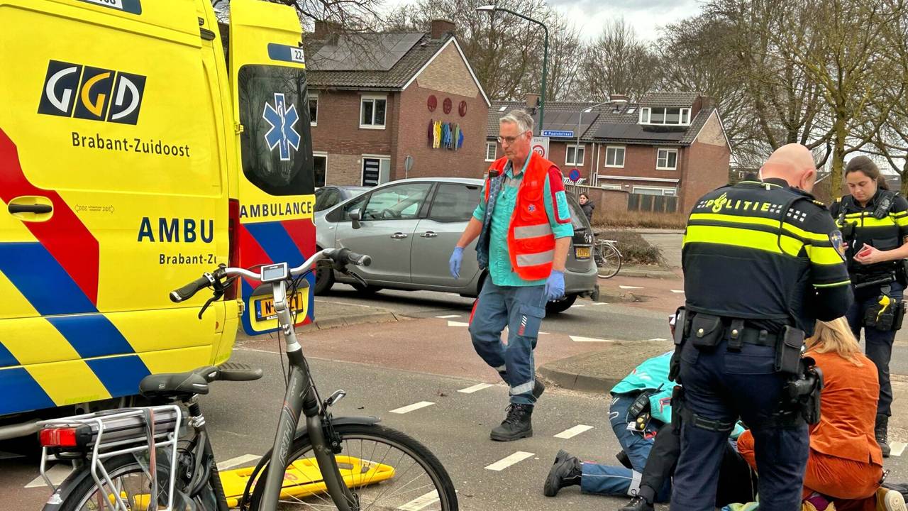 Ambulancemedewerkers en agenten buigen zich over een fietsster die in Veldhoven werd aangereden (foto: Rico Vogels/SQ Vision).