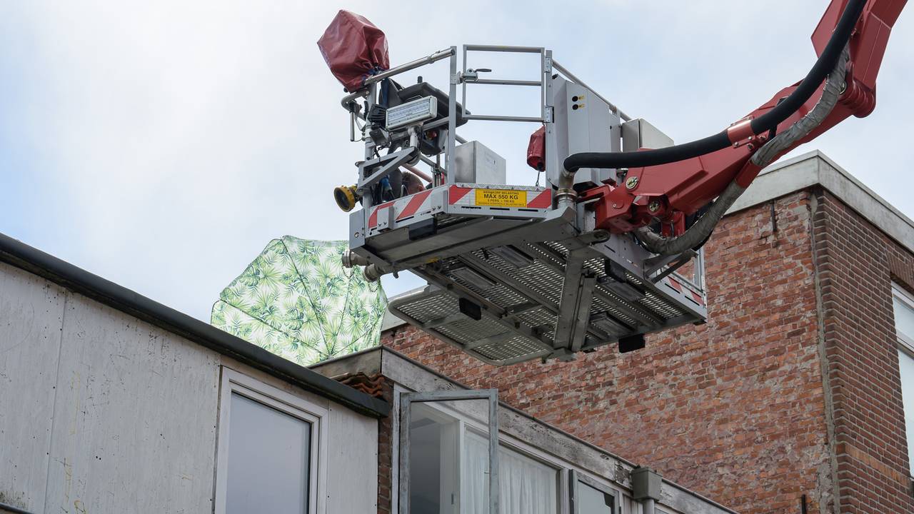 De brandweer haalt een parasol van het dak van een huis in Breda (foto: Tom van der Put/SQ Vision).