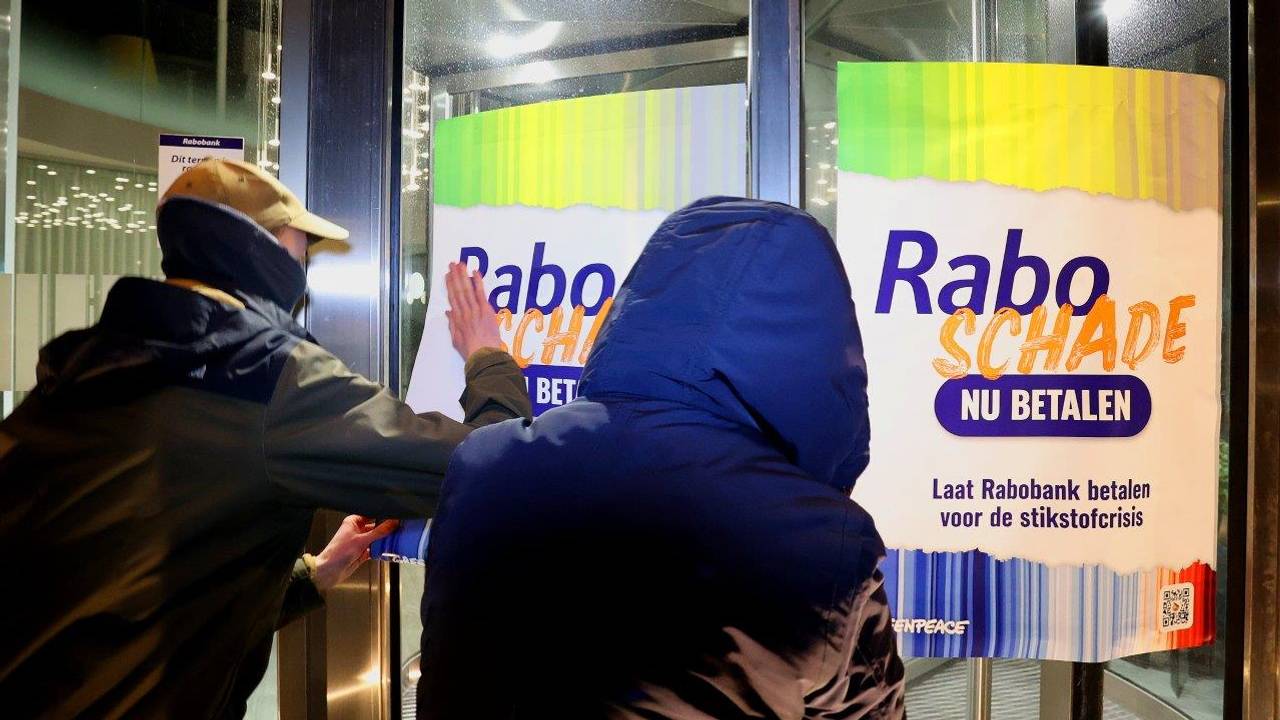 Greenpeace-leden plakken posters op Rabobankfilialen (foto: Bart Meesters).