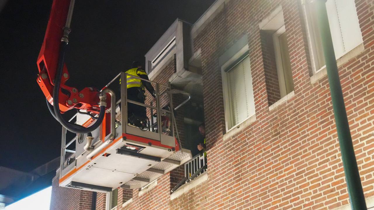 De agenten werden met een hoogwerker uit het appartement in Deurne gehaald (foto: Harrie Grijseels/SQ Vision).