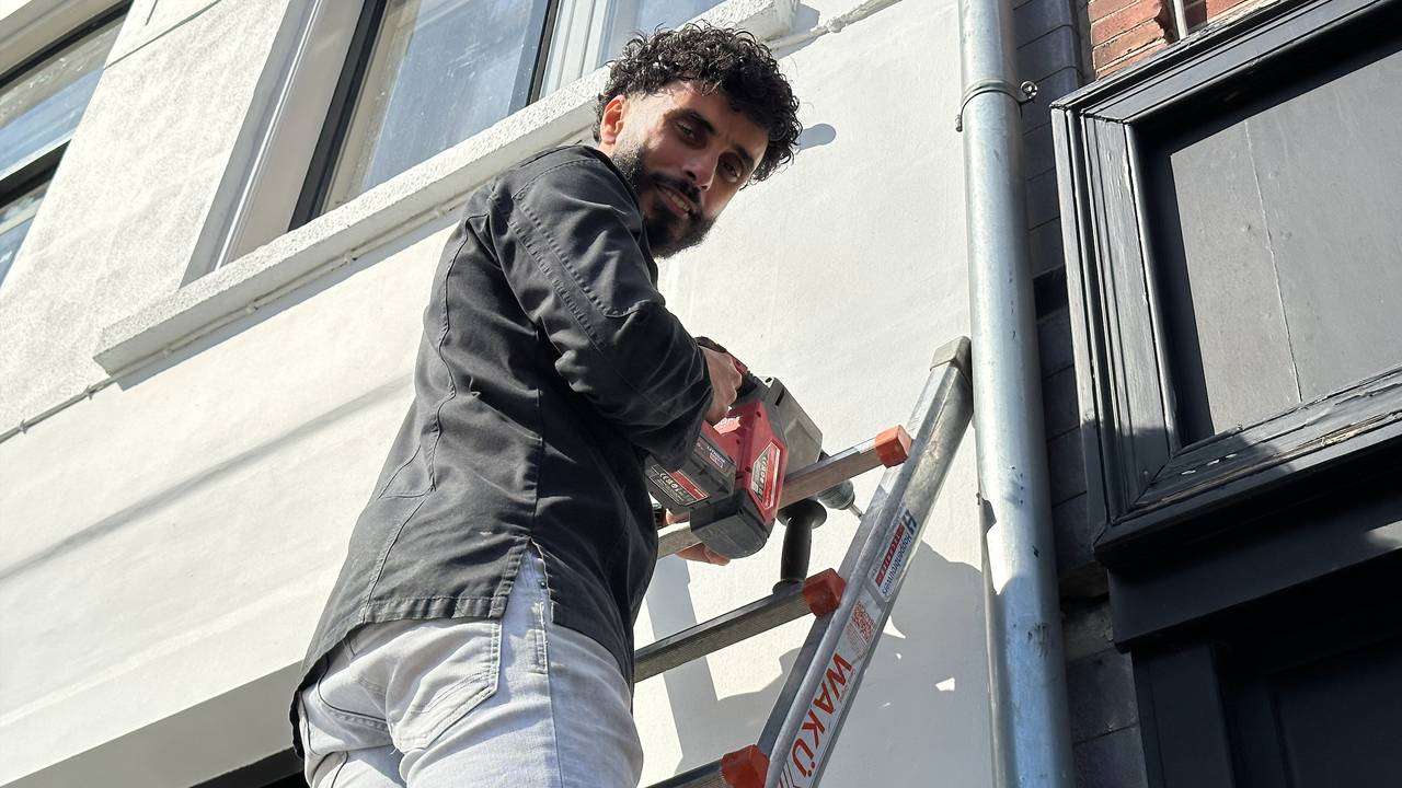 Mohamed Bittich hangt een beveiligingscamera op bij zijn viswinkel/restaurant.