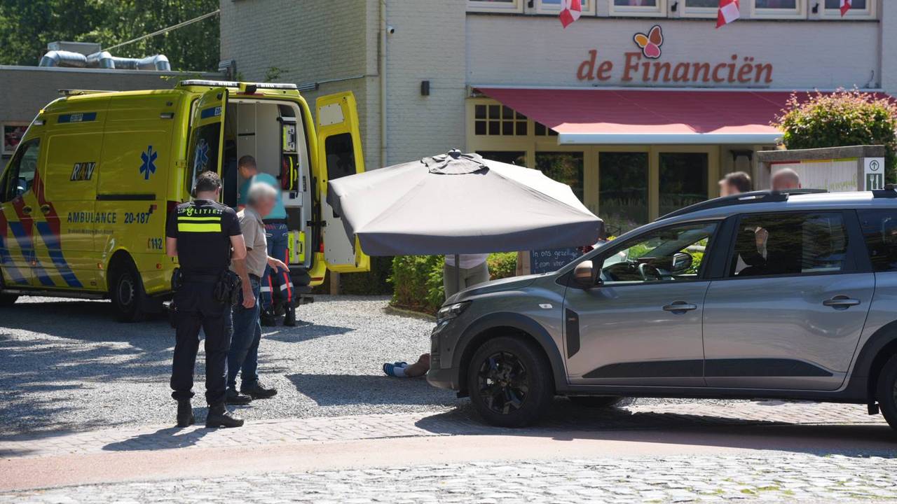Een omstander houdt een parasol boven een van de slachtoffers (Foto: Persbureau Heitink).