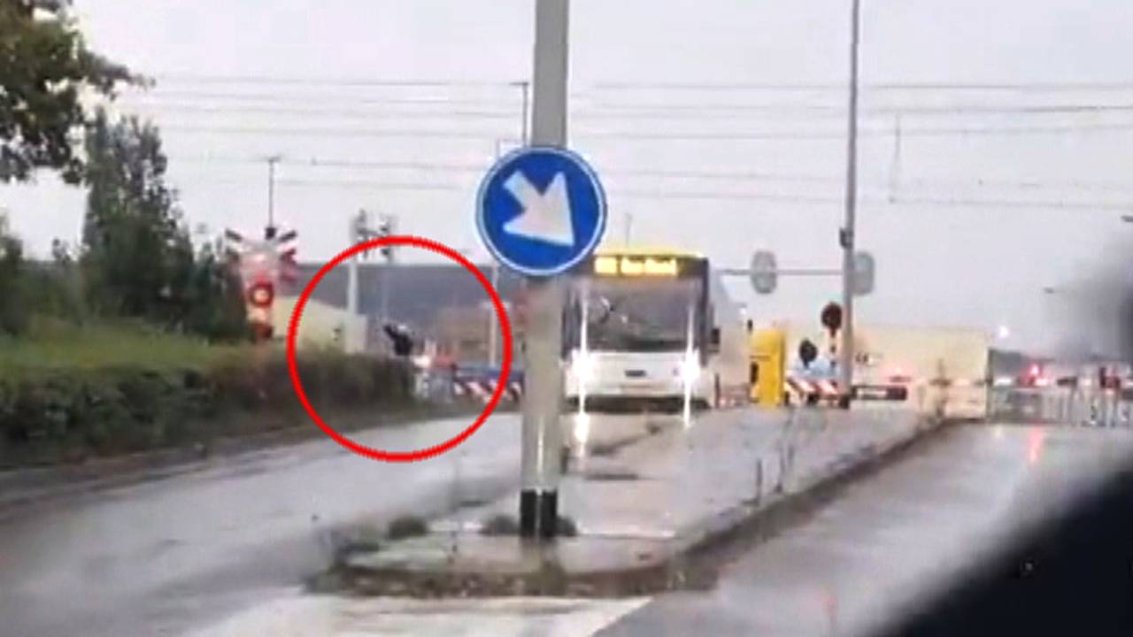 De chauffeur probeert de machinist van de aanstormende trein nog te waarschuwen.