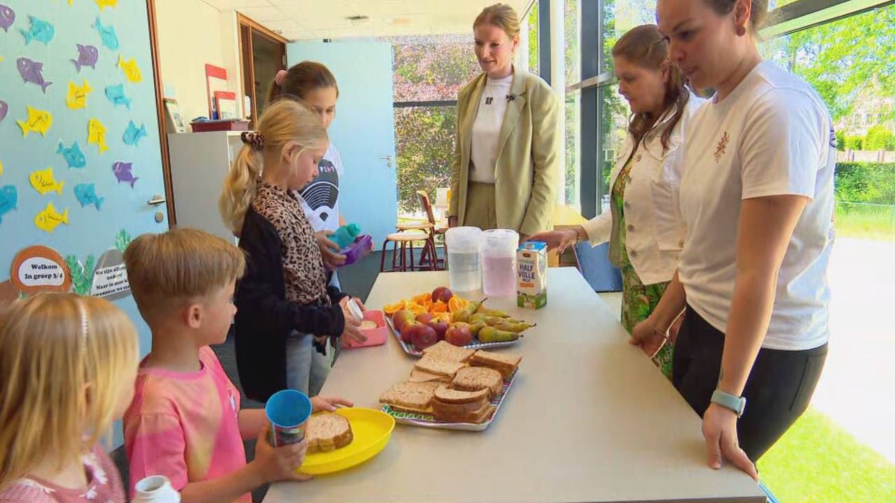 De directeur (midden) kijkt toe hoe de leerlingen smullen (foto: Noël van Hooft).