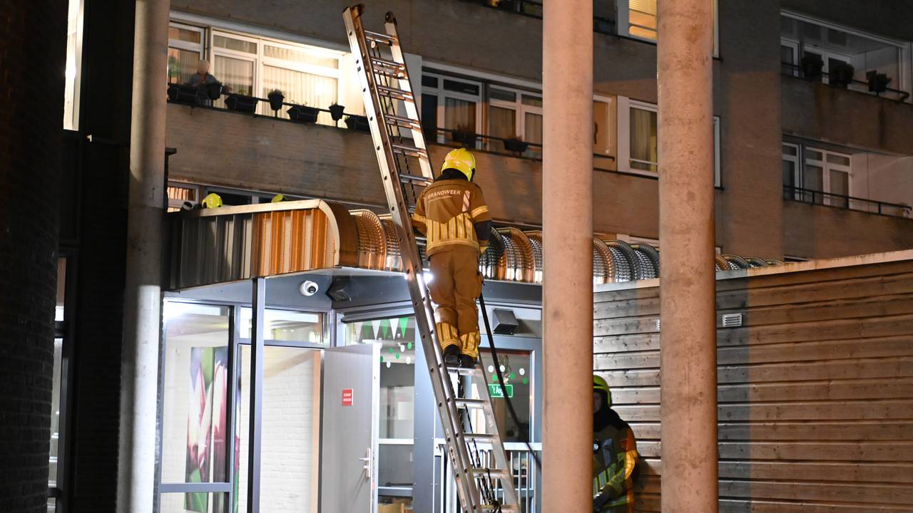 Een brandweerman stond op een ladder om de brand op het afdak van de eerste verdieping te blussen (foto: SQ Vision/Perry Roovers).