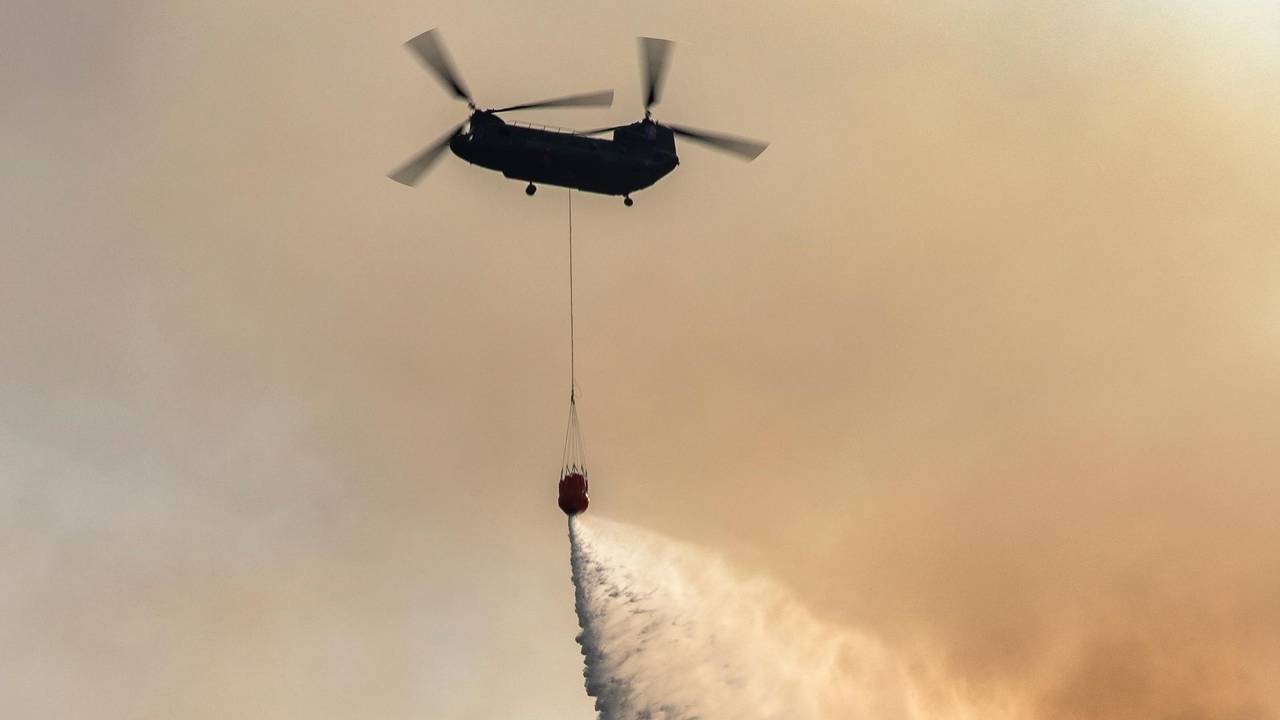 De Chinook loost water boven de brand (foto: Defensie).