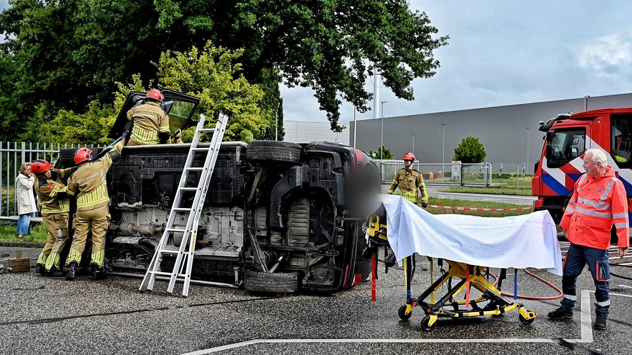 Bestelbus slaat om bij botsing op kruising, bestuurder bekneld.