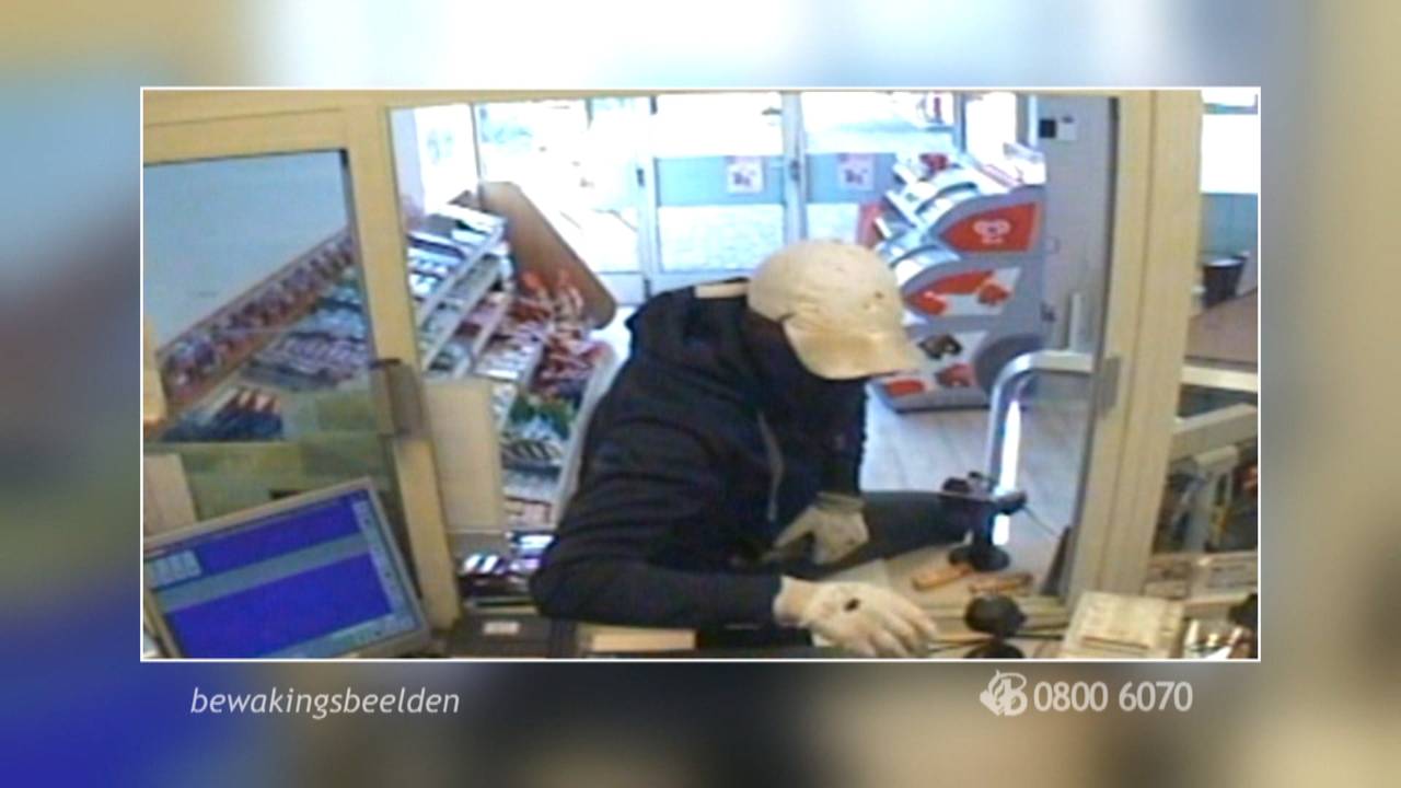 De overvaller graait de kassa leeg.