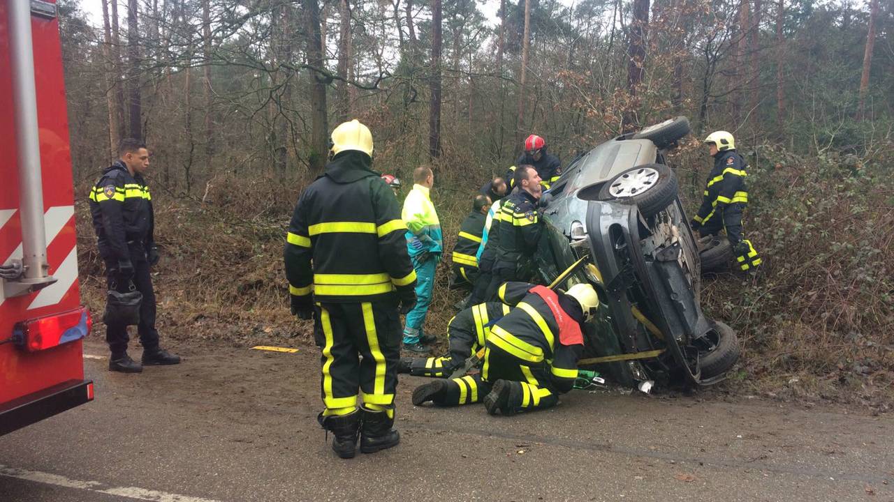 Vrouw bekneld in gekantelde auto