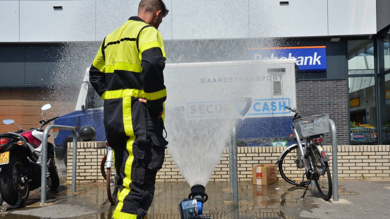 Vanwege de warmte koelt de brandweer de geldwagen met daarin twee mannen. (Foto: Perry Roovers)