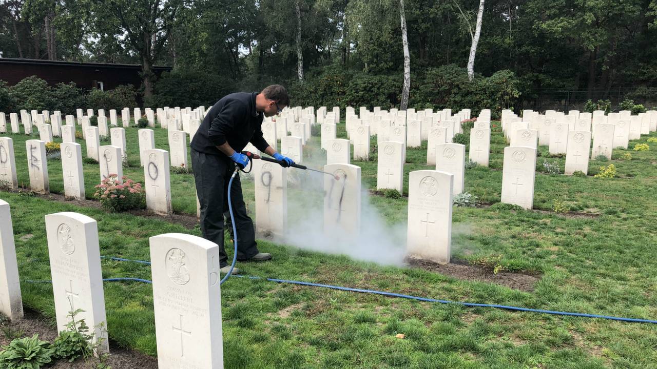 Schoonmakers proberen de graven in Mierlo schoon te maken (Foto: Imke van der Laar).