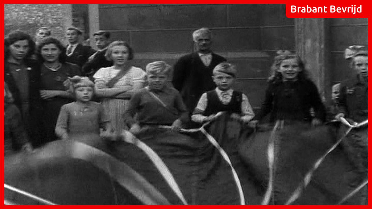 Kinderen spelen na de bevrijding met een parachute.