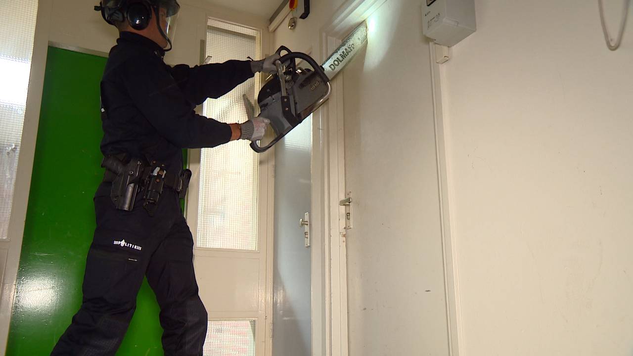 Agent sloopt een deur in het oude studentenhuis