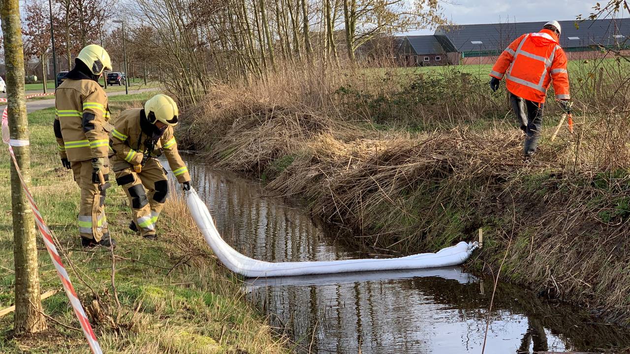 Brandweerlieden proberen met drijvende afzettingen te voorkomen dat de olie zich in de sloten verspreid. (Foto: Bart Meesters)