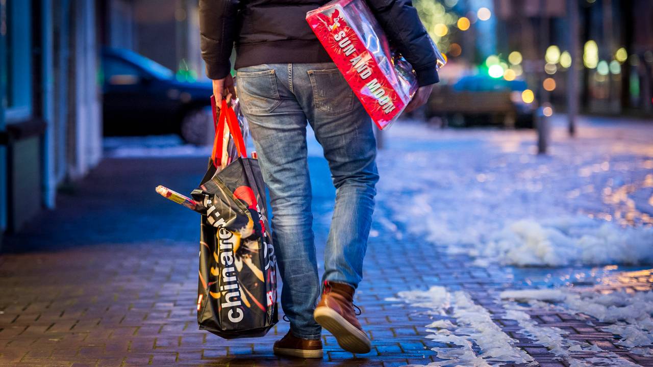 Een man loopt met vuurwerk over straat (foto: Lex van Lieshout/ANP).