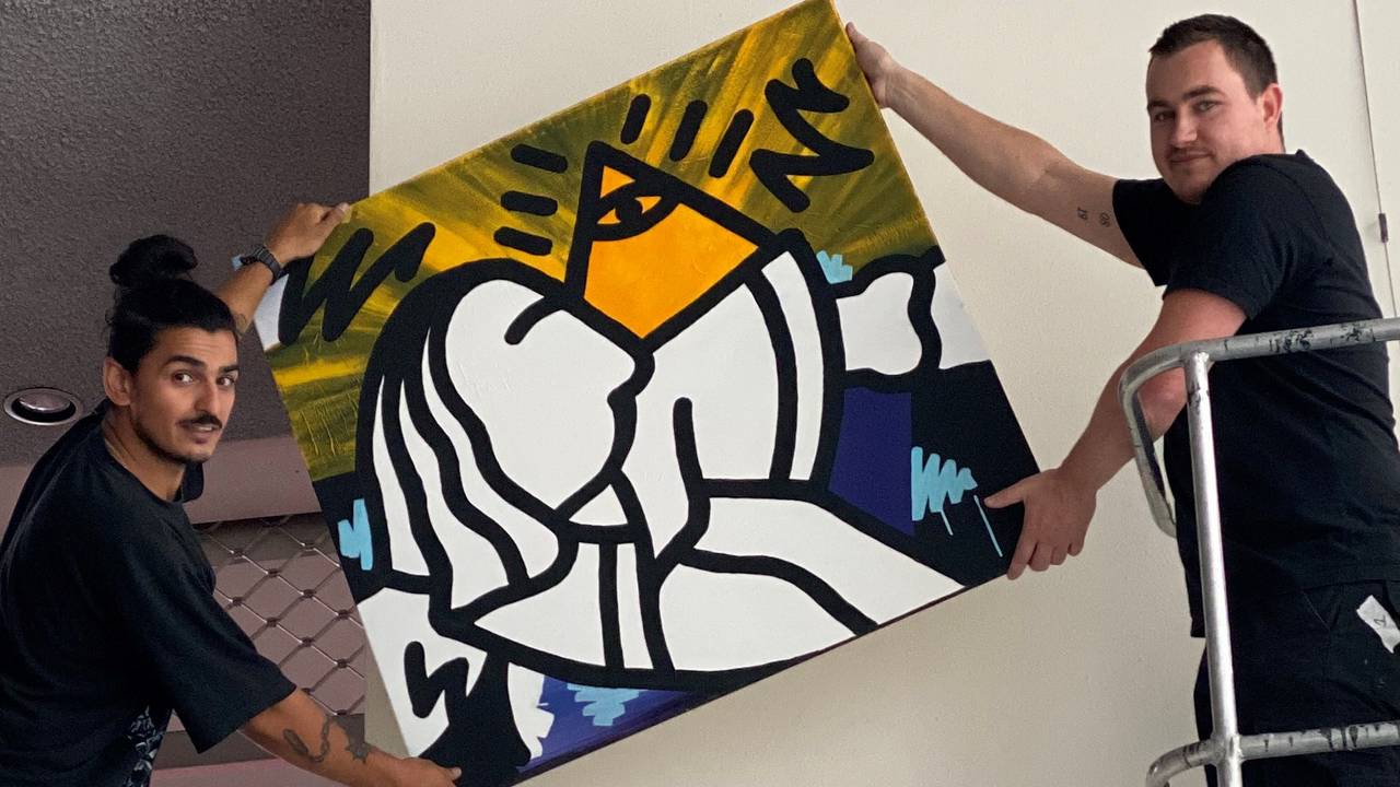 Atilla en Jerry hangen een van de 50 portretten op.