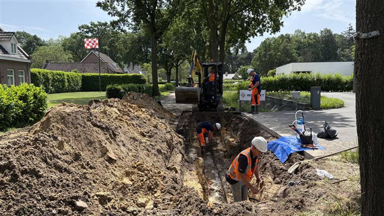In de hitte wordt de gesprongen waterleiding gerepareerd ( foto: Ruud Ritzen).