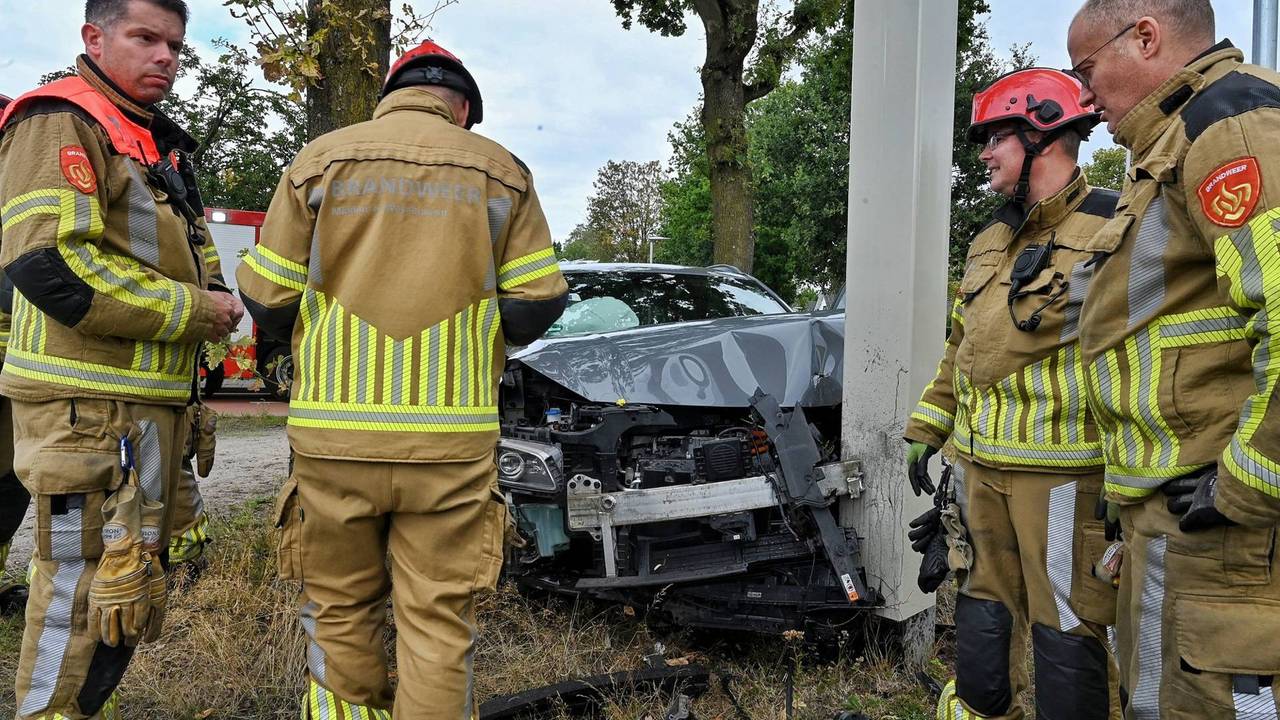 Elektrische auto botst op paal, man en vrouw uit voertuig gehaald
