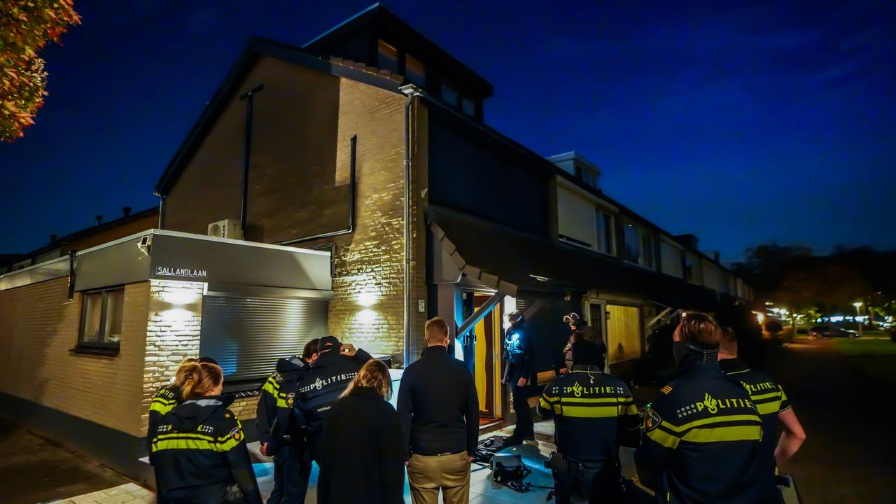 Politie zaagt gat in voordeur van huis bij inval in Eindhoven (foto: SQ Vision).