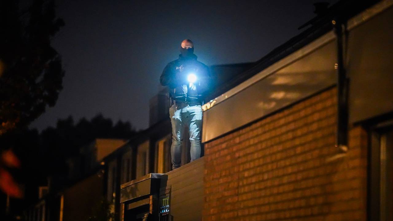 Politie zaagt gat in voordeur van huis bij inval in Eindhoven (foto: SQ Vision).