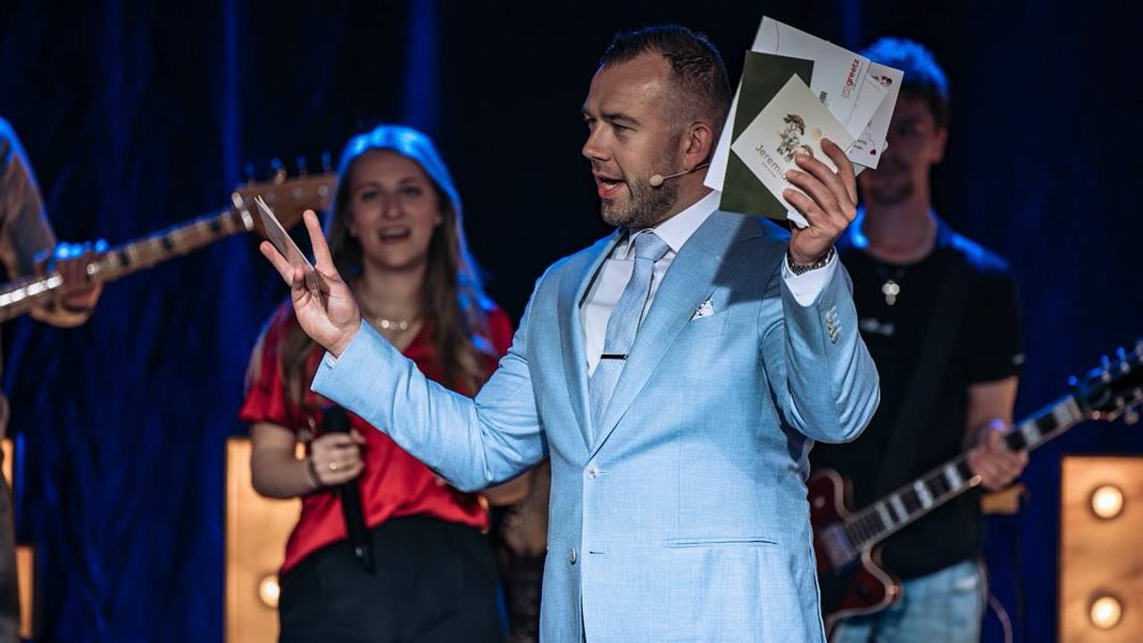 Tom de Wal met in zijn hand geboortekaartjes, tijdens een kinderwensdienst in Dussen tijdens het paasweekend (Foto: Facebook Frontrunners Ministries).
