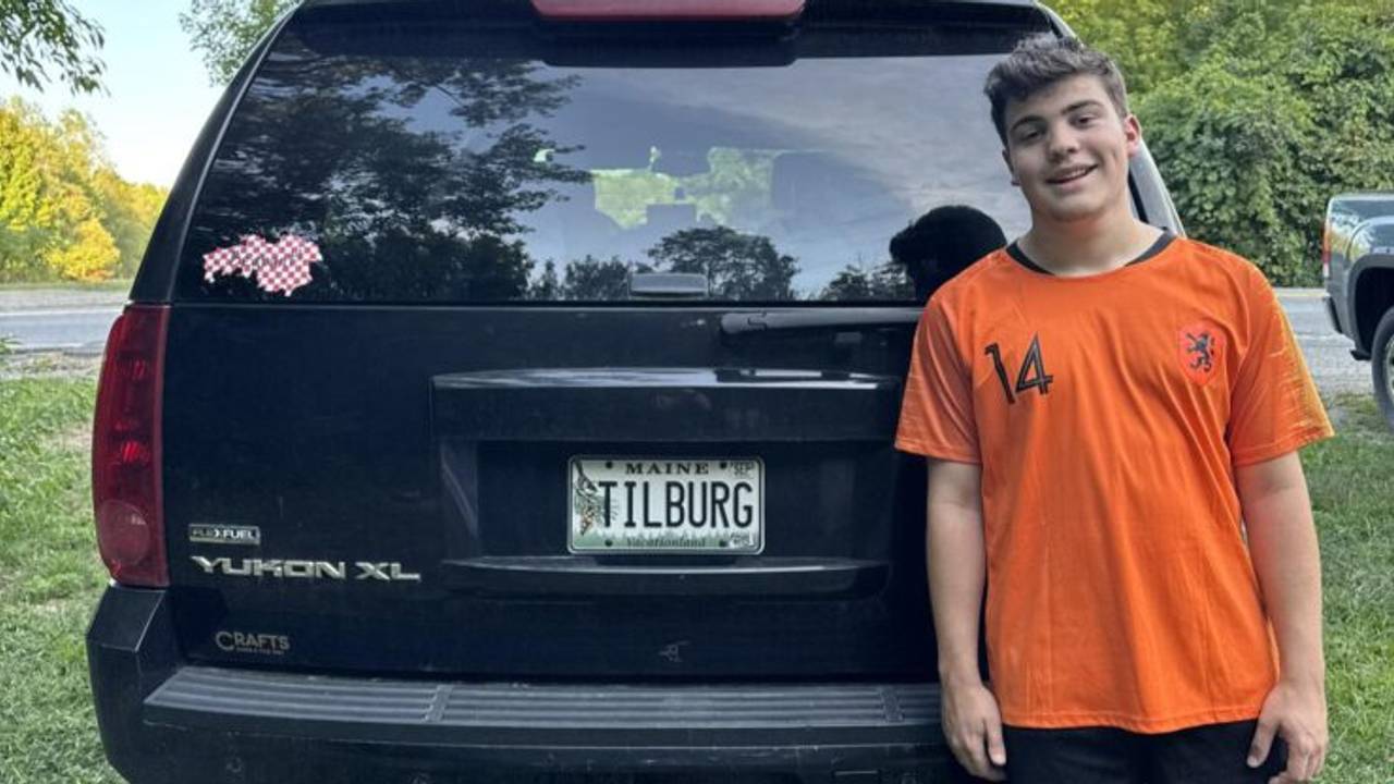 Kain staat trots bij zijn nieuwe auto met bijzonder kenteken (foto: Claudia Eekels).