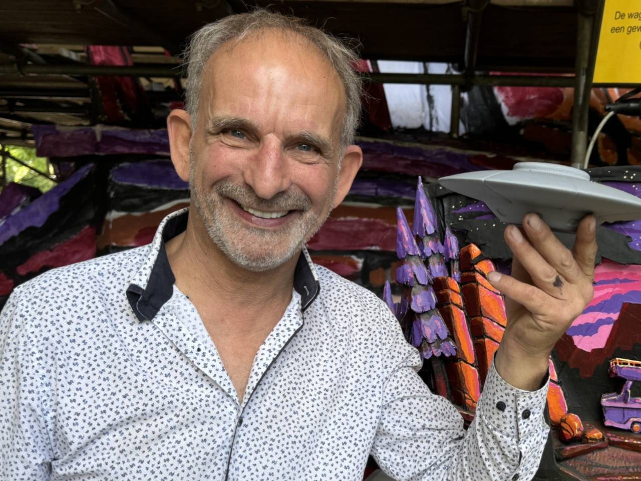 Johan Vlemmix met een miniatuurversie van de UFO, bij een maquette van de Corso-wagen in Zundert (foto: Niek de Bruijn)