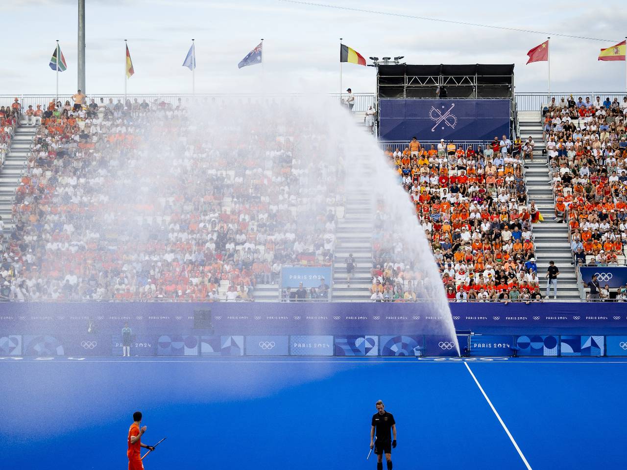 De sproeier bij het hockeyveld sprong tijdens de mannenfinale ineens aan (foto: ANP/Remko de Waal).