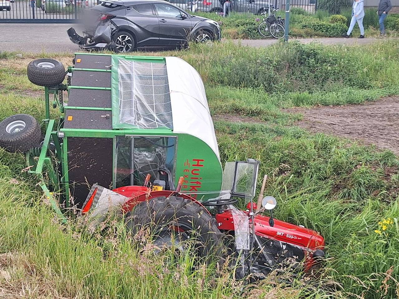 Tractor met huifkar valt in de sloot na botsing met auto