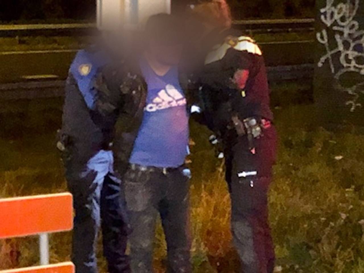 Colombiaan geboeid aan een verkeersbord door agent en boa (foto: Willem-Jan Joachems).