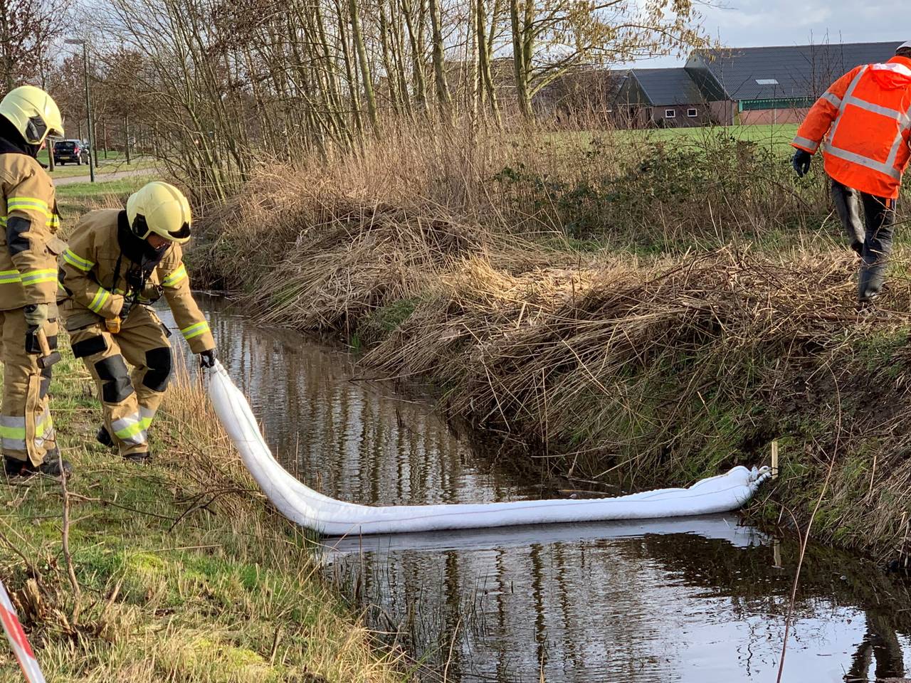 Brandweerlieden proberen met drijvende afzettingen te voorkomen dat de olie zich in de sloten verspreid. (Foto: Bart Meesters)