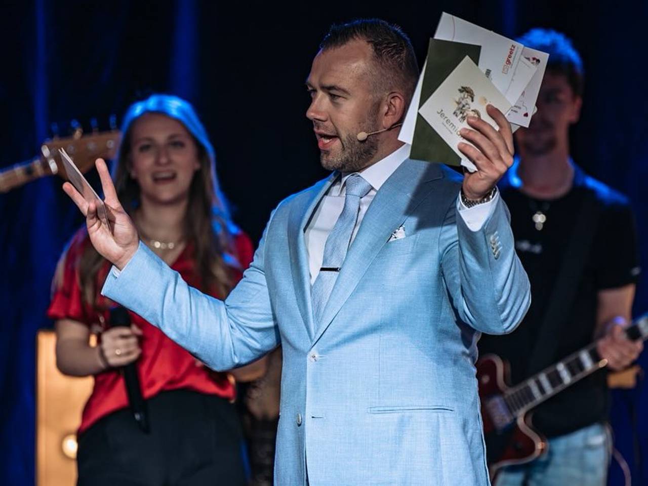 Tom de Wal met in zijn hand geboortekaartjes, tijdens een kinderwensdienst in Dussen tijdens het paasweekend (Foto: Facebook Frontrunners Ministries).