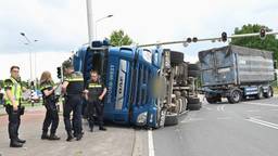 Vrachtwagen met puin kantelt op kruispunt