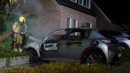 Elektrische auto in vlammen op, raam van huis springt door hitte
