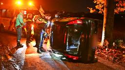 Auto schiet uit de bocht en slaat om, voorbijgangers halen duo eruit