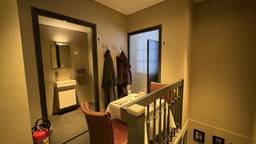 De tafel naast twee wc's, kapstok, trap en brandblusser (foto: Raymond Merkx).