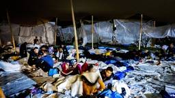 Asielzoekers sliepen in 2022 bij het overvolle aanmeldcentrum in Ter Apel in tenten voor het azc op de grond buiten (foto: ANP)