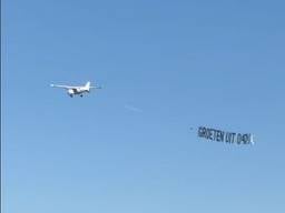 Een reclamevliegtuig met 'Groeten uit 040' vliegt over Amsterdam.