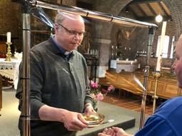 Pastoor Maickel Prasing reikt vanaf zondag de hostie uit met een plastic scherm ertussen (foto: Erik Peeters).