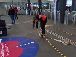 Op het station in Eindhoven worden coronastickers geplakt.