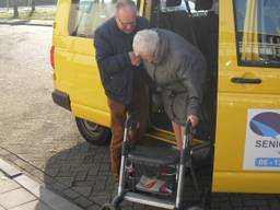 Een vrijwilliger van de Bossche Seniorenbus helpt een passagier uitstappen (foto: Seniorenbus Den Bosch)