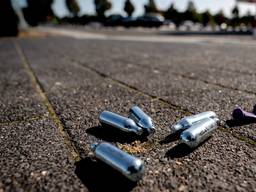 Lachgas patronen en een ballon op een parkeerplaats (Archieffoto: Sander Koning / ANP / Hollandse Hoogte).