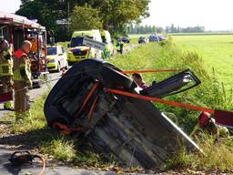 Auto rijdt achteruit sloot in, twee mensen raken gewond