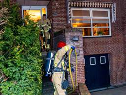 Brand onder overkapping huis, bewoners uit huis gehaald vanwege rook