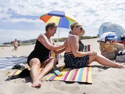 Badgasten op het strand smeren zich in met zonnebrandcrème (foto: ANP). 