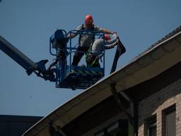 Met een hoogwerker wordt een dak aan de Biezenloop gerepareerd.