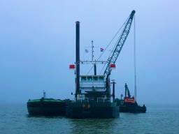 Met een schip en een ponton wordt de oude brandstofleiding opgevist (foto: Raoul Cartens).