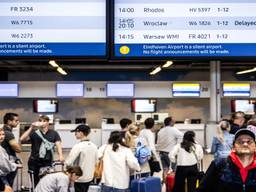 Reizigers staan bij een incheck balie terwijl er op het vertrekscherm een Transavia vlucht naar Rhodos wordt aangekondigd. (foto: ANP/ROB ENGELAAR)