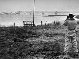Poolse militair tuurt met verrekijker naar de kapotte Moerdijkbrug (foto: archief)